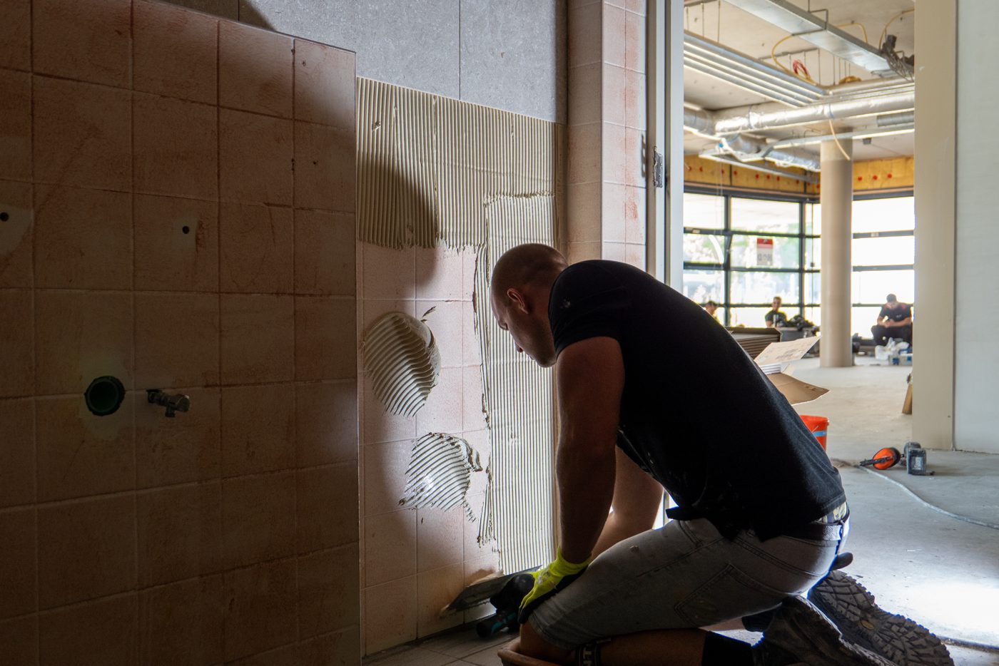 Applying tile adhesive to a wall at Pulse